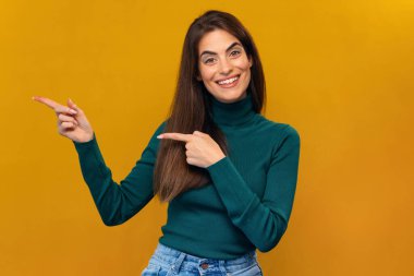 İzole edilmiş sarıda kameraya poz verirken parmaklarıyla gülümseyen güzel bir kadının görüntüsü.
