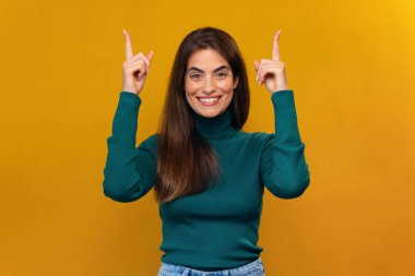 İzole edilmiş sarıda kameraya poz verirken parmaklarıyla gülümseyen güzel bir kadının görüntüsü.