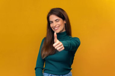 Pozitif güzel bir kadının kameraya izole edilmiş sarıda poz verirken parmaklarıyla hareket etmesi.