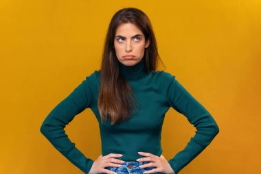 Elleri belinde, izole edilmiş sarıda kameraya poz veren sıkıcı, güzel bir kadın.