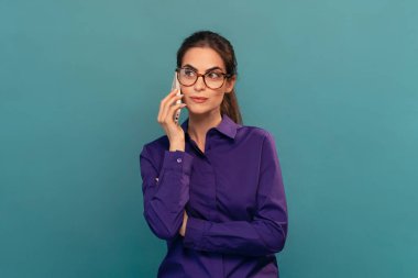 Güzel bir kadının kameranın önünde mavi ışıkta akıllı telefonunu kullanarak gülümsemesi.