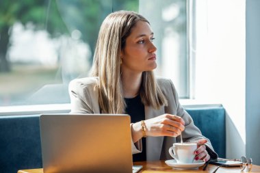 Bir kafede kahvaltı yaparken onu laptop ile çalışan güzel genç kadın görüntüsünü