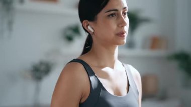 Evdeki oturma odasında müzik dinlerken ağırlık çalışan genç bir kadının videosu.