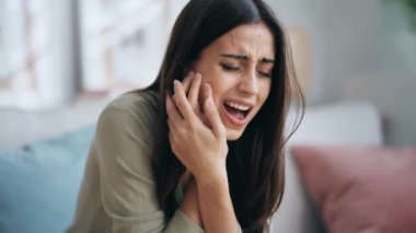 Evdeki koltukta oturan dişleri ağrıyan yorgun ve güzel bir kadının videosu.