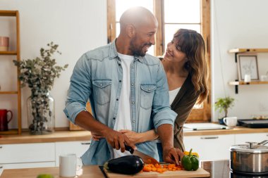 Evdeki mutfakta sebze keserken güzel ve romantik bir çiftin kucaklaşması.