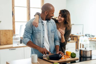 Evdeki mutfakta sebze keserken güzel ve romantik bir çiftin kucaklaşması.
