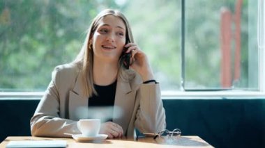 Kahve dükkanında cep telefonuyla mesajlaşan genç bir iş kadınının videosu.