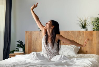 Shot of beautiful young woman stretching in the bed after wake up clipart