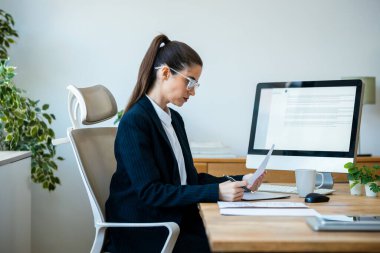 Ofisteki bazı fatura ve belgelere bakarken iş kadınının bilgisayarla çalıştığı fotoğraf