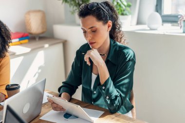 Shot of beautiful business woman working with laptop in a modern startup clipart