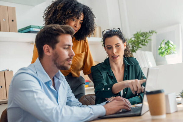 Снимок бизнес-людей, работающих с ноутбуком и говорящих о том, что они новый проект вместе в офисе.