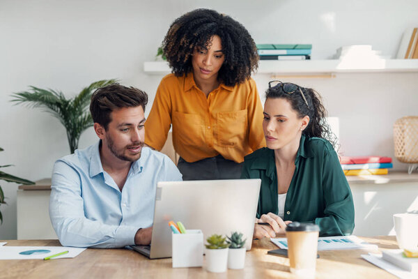 Снимок бизнес-людей, работающих с ноутбуком и говорящих о том, что они новый проект вместе в офисе.