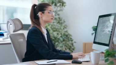 Ofiste bilgisayarla çalışan konsantre bir iş kadını videosu.