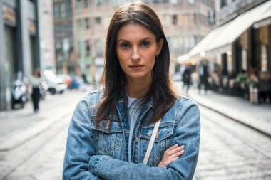 Caddenin ortasında kameraya bakarken ciddi şekilde çekici bir kadının poz vermesi.