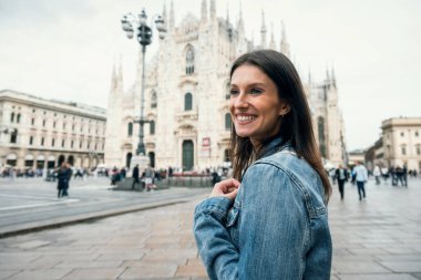 Milan sokaklarını gezerken katedralin önünde poz veren güzel bir kadın.