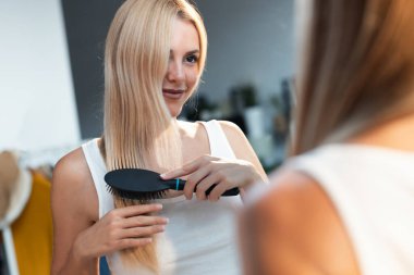 Onun ayna önünde uzun saçları fırçalama güzel genç kadın portresi