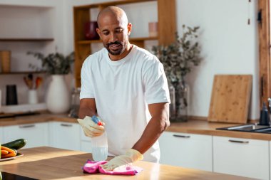 Çekici yakışıklı bir adamın evdeki mutfağı temizlemesi.