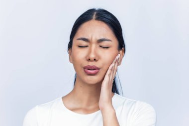 Yüzüne dokunan dişleri ağrıyan güzel bir kadın resmi.