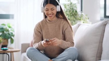Motive olmuş genç bir kadının evdeki kanepede dans ederken akıllı telefonuyla müzik dinlediği bir video.