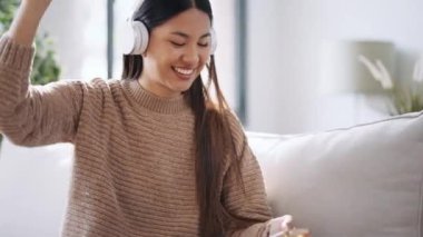 Motive olmuş genç bir kadının evdeki kanepede dans ederken akıllı telefonuyla müzik dinlediği bir video.