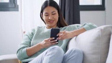 Evdeki kanepede dizüstü bilgisayarla çalışan hoş bir kadının videosu..