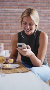 Evdeki mutfakta akıllı telefon kullanarak suşi yiyen genç bir kadının videosu.