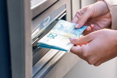 Güzel genç bir kadının şehirde kredi kartıyla ATM 'den para çekmesine yakın çekim.