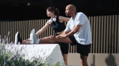 Şehirde koşmadan önce esneme hareketleri yapan çekici ve atletik çiftin videosu.