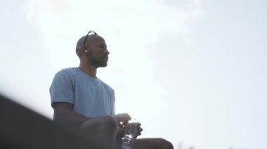 Şehirde koşuya çıkmadan önce kulaklıkla müzik dinleyen atletik adamın videosu.