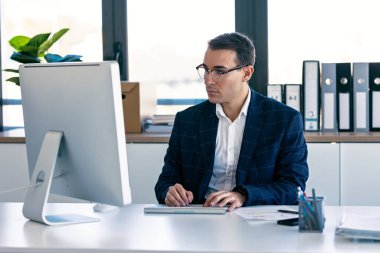 Modern bir girişimde dizüstü bilgisayarla çalışan konsantre ve zarif bir iş adamı..