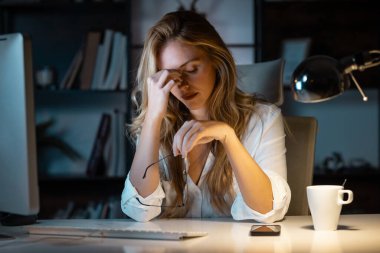 Ofiste bilgisayarla çalışırken başı ağrıyan zarif bir iş kadınının fotoğrafı.