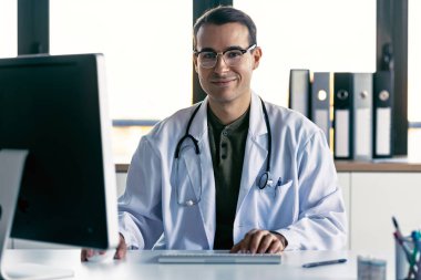 Tıbbi konsültasyonda bilgisayarla çalışan zeki erkek doktor.