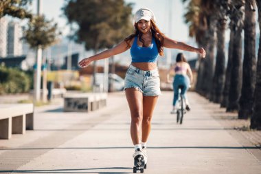 Sahilde paten kayarken kulaklıkla müzik dinleyen güzel bir kadın. 