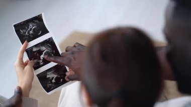 Evde kanepede otururken bebek ultrasonu izleyen çekici hamile çiftin videosu..