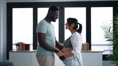 Güzel bir çiftin bir arada durup, evdeki pencerelerin yanında karnına dokunduğu bir video..