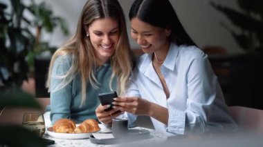 Kahve dükkanında akıllı telefon kullanan iki güzel kadının videosu.