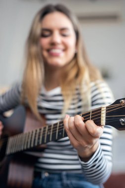 Gitar çalan ve evdeki oturma odasında tıngırdayan oldukça etkili bir kadının fotoğrafı.