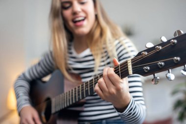 Gitar çalan ve evdeki oturma odasında tıngırdayan oldukça etkili bir kadının fotoğrafı.