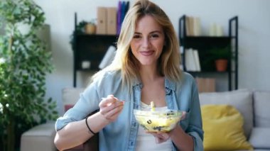 Sağlıklı makarna salatası yiyen gülümseyen bir kadının videosu.