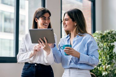 Ofiste dijital tabletini çiğnerken iki güzel iş kadınının ara verip fotoğraf çektirmesi.