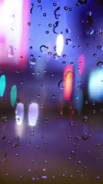 Şehrin dikey videosunda fırtınada bir pencereden aşağı doğru yağmur yağıyor