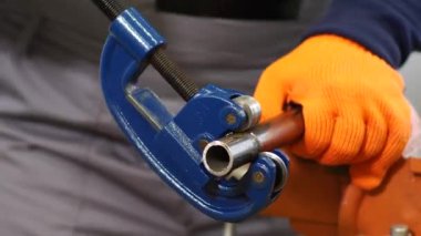 Tesisatçı boruyla metal bir boru kesiyor.