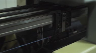Tekstil fabrikasında kumaş üreten otomatik dokuma makinesinin yakın çekim görüntüsü.