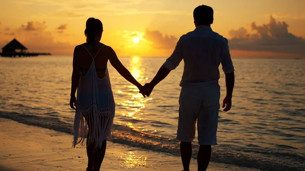 日没時にビーチで手を繋いでいるカップルのトリミングされた画像 — ストック写真