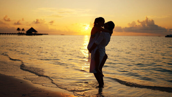 Male And Female On Beach In Sunset Together. Romantic Vacation