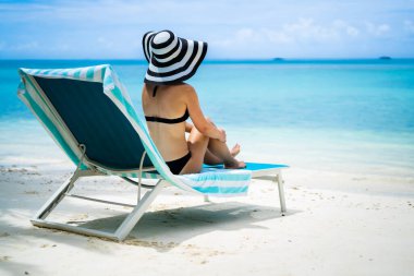 plajda şezlong üzerinde bikini güneşlenme içinde genç bir kadın