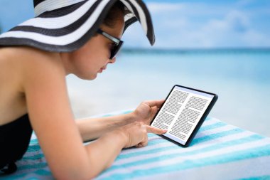 Plajda Tablet Üzerinde E-Kitap Okuyan Kadın