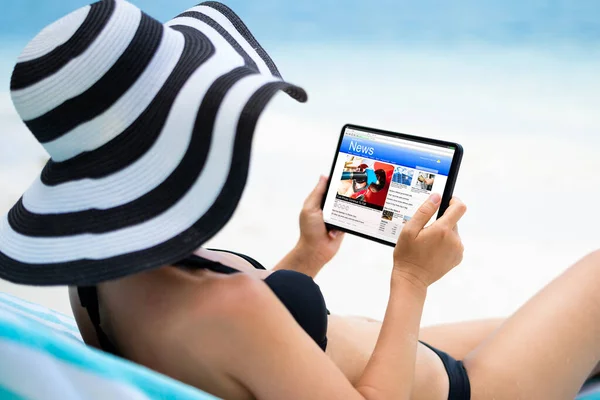 泳滩的妇女在使用数码电话阅读新闻 — 图库照片