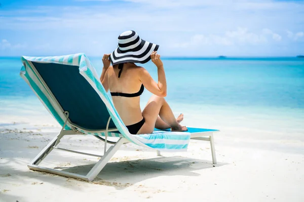 比基尼在沙滩的躺椅上晒日光浴的年轻女子 — 图库照片