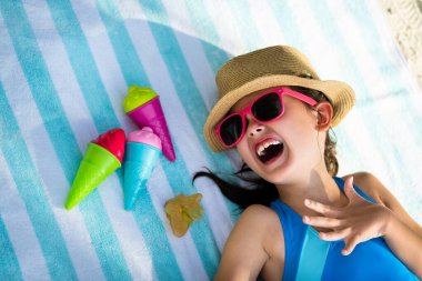 Sahilde güneş gözlüklü çocuk.